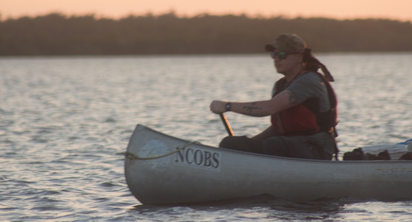 a person paddles a canoe on an outward bound veterans expedition.